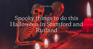 Skeleton sitting at a desk in the dark with candles burning