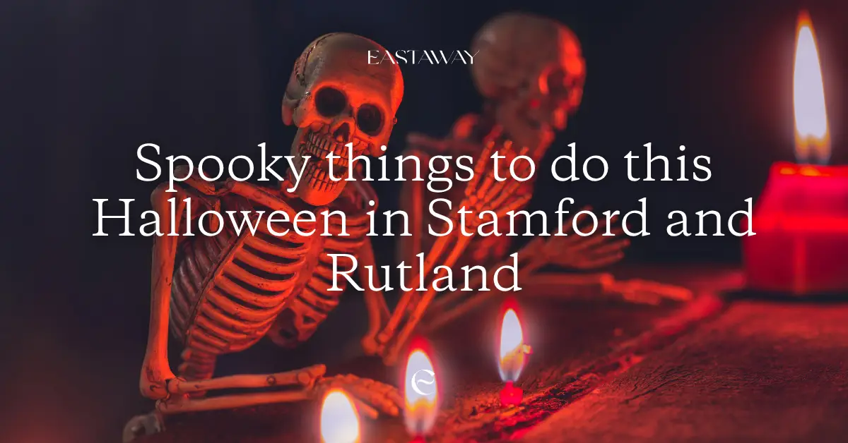 Skeleton sitting at a desk in the dark with candles burning
